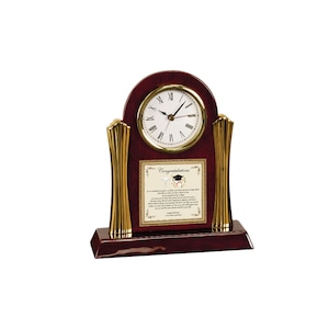 May include: A mahogany wood clock with gold accents and a white face. The clock has a plaque with the text "Congratulations" and a graduation cap and stethoscope graphic.