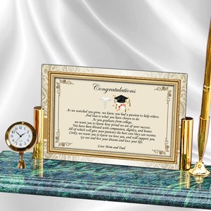 May include: A green marble desk set with a gold pen, a gold pen holder, a gold clock, and a framed certificate with the text "Congratulations". The certificate has a graduation cap and a medical symbol on it. The text on the certificate reads: "As we watched you grow, we knew you had a passion to help others. And that is what you have chosen to do. As you graduate from college, we want you to know how proud we are of your success. You have been blessed with compassion, dignity, and honor. All of which will give your patients the best care they can receive. Cindy, we want you to know we love you, and will support you. Go out and love your dreams and love your life. Love Mom and Dad."