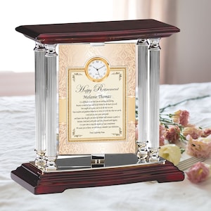 May include: A wooden and crystal retirement clock with a gold-framed message that reads "Happy Retirement Melanie Thomas." The clock has a gold-colored clock face and two crystal pillars. The base and top are made of dark wood.