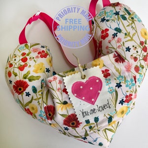 May include: A heart-shaped pillow with a floral print and a pink heart tag that says "You are loved".