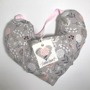 May include: A gray heart-shaped pillow with a floral pattern and a white tag that says "take heart".