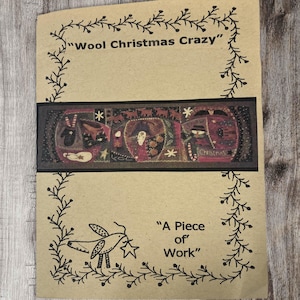 May include: A brown paper pattern booklet with a title that reads "Wool Christmas Crazy" and a smaller title that reads "A Piece of Work". The booklet features a colorful illustration of a Christmas-themed quilt with a variety of patterns and colors.