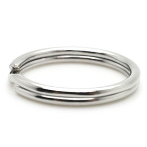 May include: A close-up of a silver-colored split key ring. The key ring is made of three connected circular bands. The split in the ring is visible at the top left. The background is white.