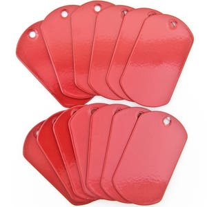 May include: A collection of red dog tags, rectangular with rounded corners and a hole at the top. The tags are arranged in two groups, fanned out to show their shape and colour. Each tag is approximately 5 cm long.
