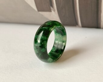 May include: A green jade ring with a marbled pattern. The ring is wide and has a polished finish.