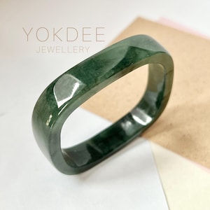 May include: A square-shaped jade bangle with a dark green color. The bangle is polished and has a glossy finish.