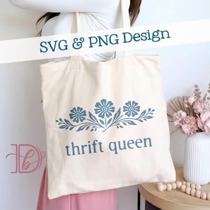 Puede incluir: Bolso tote de color crema con un diseño floral azul y las palabras "thrift queen" impresas en la parte delantera. El texto "SVG & PNG Design" está impreso en la parte superior.