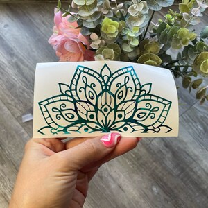 May include: A teal green mandala design on a white background. The mandala is a half circle with intricate details and a floral pattern.