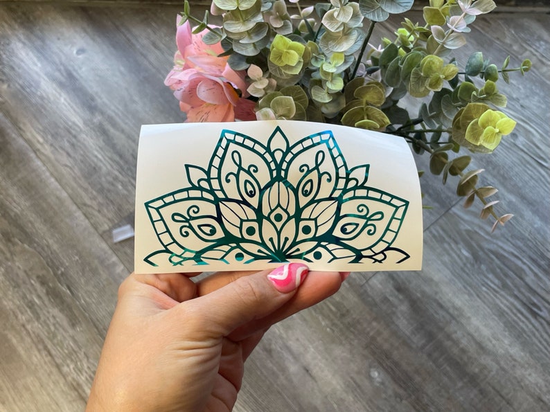 May include: A teal green mandala design on a white background. The mandala is a half circle with intricate details and a floral pattern.