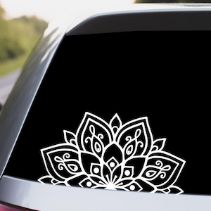 May include: A white mandala design decal on a black car window. The mandala is a half circle design with intricate details.