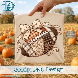 May include: A beige t-shirt featuring a graphic of an American football decorated with a large bow. The football has a patchwork design with various patterns including plaid, floral, gingham, and leopard print in shades of brown, orange, and cream.