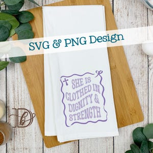 May include: White kitchen towel with the text "SHE IS CLOTHED IN DIGNITY & STRENGTH" in a purple wavy design. The towel is on a wooden chopping board. The words "SVG & PNG Design" are also visible.