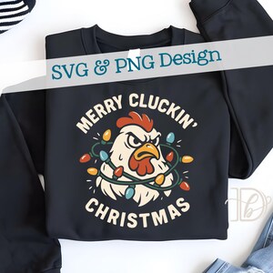 May include: Black sweatshirt featuring a cartoon chicken with Christmas lights and the text "MERRY CLUCKIN' CHRISTMAS". The design includes the text "SVG & PNG Design" in a banner. The chicken has a red comb and wattle.