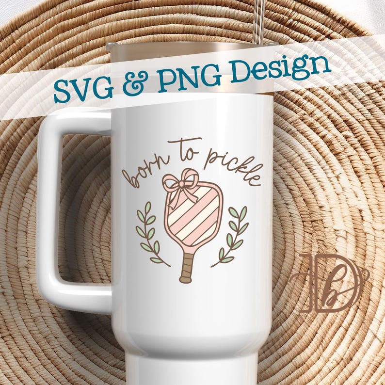 May include: White travel mug with a handle, featuring the text "born to pickle" in a script font. The design includes a pickleball paddle with pink and white stripes, a bow, and laurel branches. The words "SVG & PNG Design" are at the top.