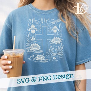 Op de afbeelding: Lichtblauw T-shirt met een wit kruisontwerp omringd door bloemen- en libellenillustraties. De tekst "SVG & PNG Design" staat onderaan. Het shirt is een casual, comfortabele stijl.