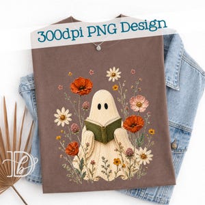 May include: A brown t-shirt featuring a graphic of a cream-colored ghost reading a green book, surrounded by various colorful wildflowers including red poppies and white daisies. The text 300dpi PNG Design is printed at the top of the shirt.