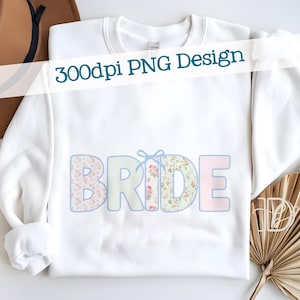 Puede incluir: Sudadera blanca con la palabra "BRIDE" en colores pastel. Las letras están decoradas con estampados florales y de cuadros, delineadas en azul y acentuadas con un lazo azul. El texto "300dpi PNG Design" se muestra en la parte superior.