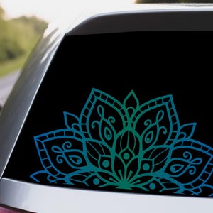 May include: A blue and green mandala design decal for a car window. The decal is a half circle and features intricate details.
