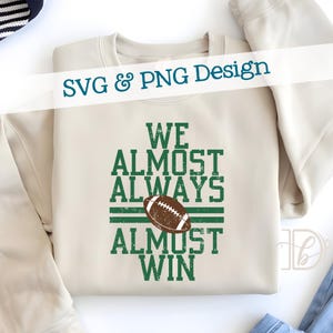 May include: A cream-colored sweatshirt with the text "WE ALMOST ALWAYS ALMOST WIN" in green, along with a brown football graphic. The words "SVG & PNG Design" are written across the top in white.