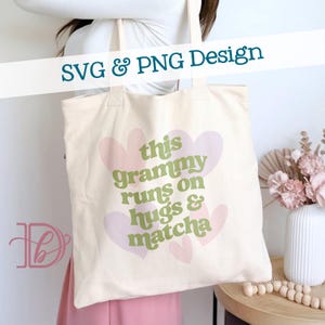 Könnte beinhalten: Cremefarbene Tragetasche mit dem Text "this grammy runs on hugs & matcha" in Grün und Rosa. Das Design umfasst rosa Herzformen. Oben steht "SVG & PNG Design".