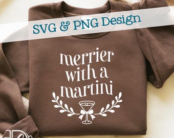 May include: A brown sweatshirt featuring the white text "merrier with a martini", a martini glass, and a leaf design. The words "SVG & PNG Design" are across the top. The sweatshirt is folded.