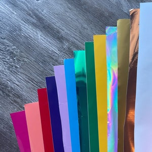 May include: A collection of 12 different colored vinyl sheets, including pink, red, purple, blue, green, yellow, gold, iridescent, and white.