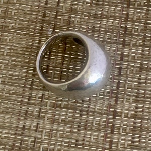 May include: A silver ring with a rounded, smooth, and slightly textured surface.