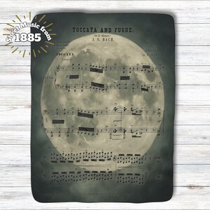May include: Sheet music from 1885 featuring the composition "Toccata and Fugue" by J.S. Bach. The sheet music is set against a backdrop of a full moon, with the text "Piano" visible. The overall color scheme is a muted, vintage aesthetic.