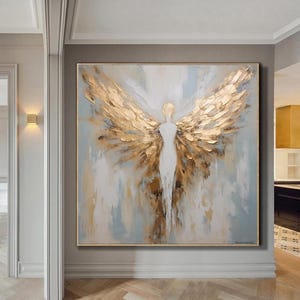 Op de afbeelding: Abstracte schilderij van een figuur met grote gouden vleugels op een witte en blauwe achtergrond.