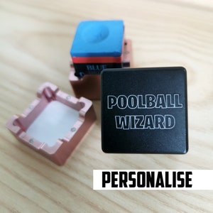 May include: Black square with the text "POOLBALL WIZARD" in white lettering. A pink and white chalk holder is in the background. The text "PERSONALISE" is below the square.