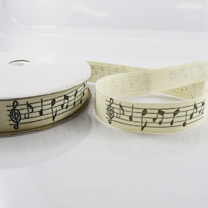 May include: Cream coloured ribbon with black musical notes and a treble clef printed on it.