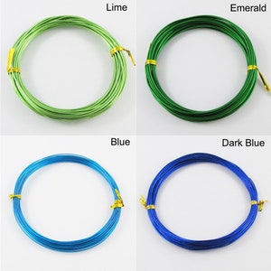 Op de afbeelding: Vier spoelen met gekleurde draad, elk gewikkeld in een cirkel. De kleuren zijn limoengroen, smaragdgroen, blauw en donkerblauw.