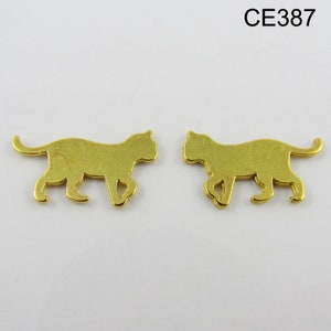 Puede incluir: Dos abalorios de metal dorado en forma de silueta de gato. Los abalorios miden aproximadamente 2,5 cm de largo y 1,25 cm de ancho.