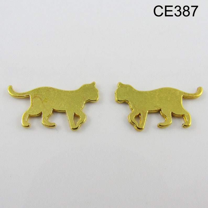 Puede incluir: Dos abalorios de metal dorado en forma de silueta de gato. Los abalorios miden aproximadamente 2,5 cm de largo y 1,25 cm de ancho.