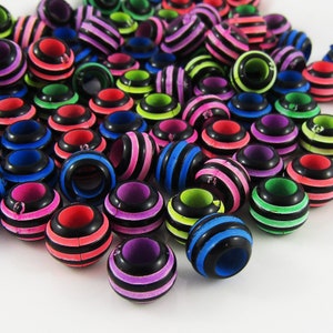 May include: A large group of colourful plastic beads with black stripes. The beads are arranged in a random pattern and are all the same size.