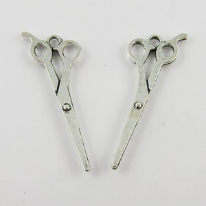 May include: Two silver-toned metal scissor charms with a loop at the top for attaching to jewellery or crafts.