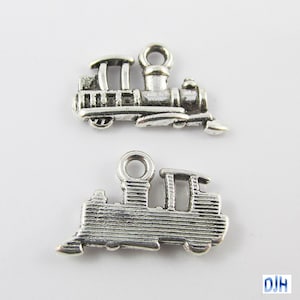 May include: Two silver-toned metal train charms. Each charm features a detailed design of a train engine with wheels, a smokestack, and a cab.