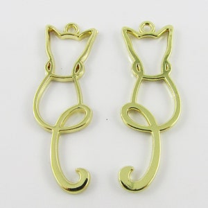 May include: Two gold metal cat outline charms with a loop at the top for hanging.
