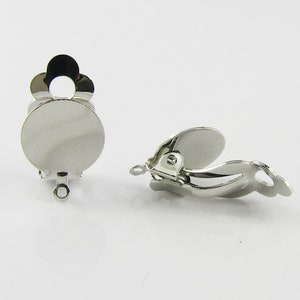 May include: Silver tone earring clip on findings with a round pad for attaching a cabochon or other embellishment.