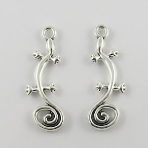 May include: Two silver-toned lizard charm pendants with a curled tail. The charms have a loop at the top for attaching to jewellery.