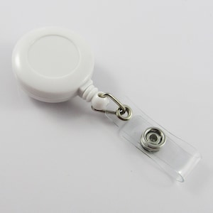 May include: White retractable badge holder with a clear strap and a silver metal clip.