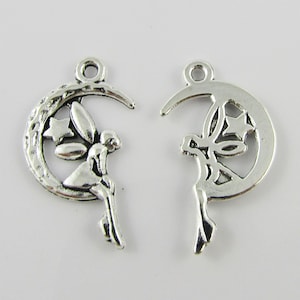 May include: Two silver-colored charms, each featuring a crescent moon design with a fairy and stars. The charms are detailed with cut-out designs and a loop at the top for attaching to jewelry or other crafts.