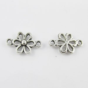 May include: Two silver-toned metal flower-shaped connector charms with three jump rings. The charms are ideal for adding a touch of elegance to jewellery making projects.