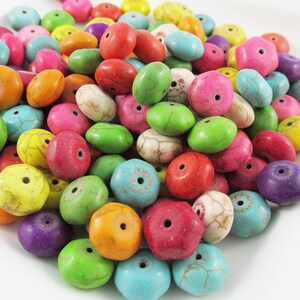 May include: A large pile of colourful, round, and flat beads with a hole in the centre. The beads are made of a mottled material, with a variety of colours including turquoise, green, red, pink, yellow, and purple.