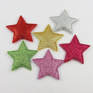 May include: Six glittery star-shaped embellishments in red, green, gold, silver, pink, and fuchsia.