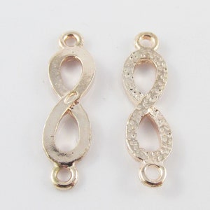 May include: Two gold-tone infinity symbol connector charms. One charm has a smooth finish, while the other has a textured finish.