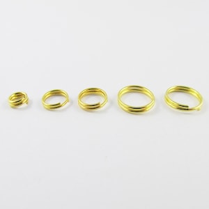 May include: Four gold jump rings of different sizes. The rings are made of metal and have a smooth finish.