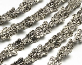 May include: A silver chain of metal butterfly charms. The chain is made of many small, detailed butterfly charms that are linked together.