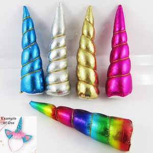 May include: Four unicorn horn headbands in different colours: blue, silver, gold, and pink. The horns are spiral shaped and have gold trim. The headbands are made of felt and are approximately 15 cm long.