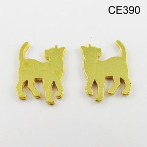 Puede incluir: Dos abalorios de metal dorado en forma de gato, cada uno con una silueta detallada de un gato de pie sobre sus cuatro patas. Los abalorios son id&eacute;nticos y tienen un acabado liso y brillante.
